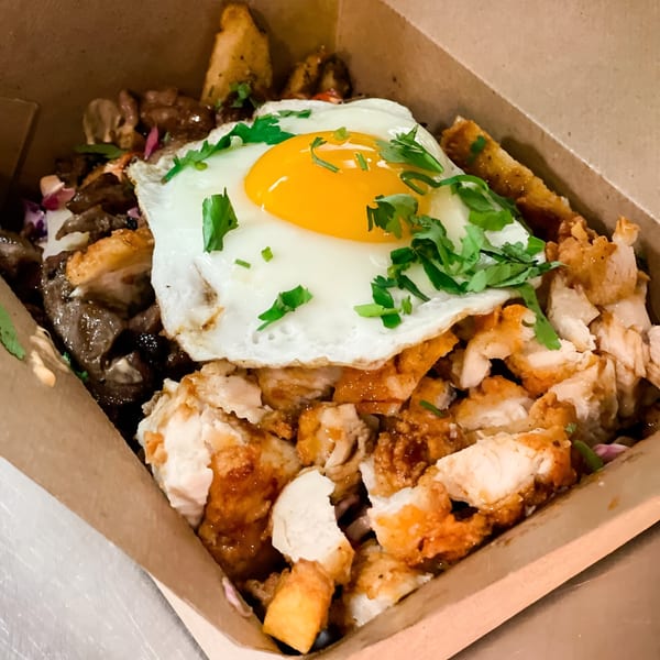 Nuri Fusion Street Kitchen's fried chicken and beef dish topped with a sunny-side-up egg and cilantro.