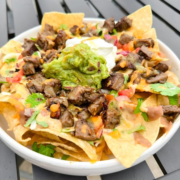 Nuri Fusion Street Kitchen's beef nachos, topped with guacamole, sour cream, and fresh cilantro.